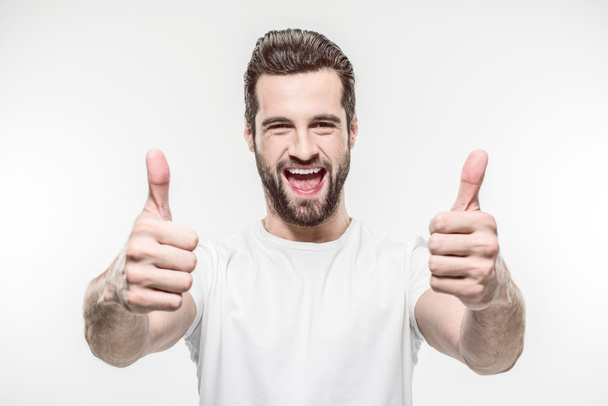 šťastný mladý muž ukazuje palec nahoru izolované na bílém - Fotografie, Obrázek