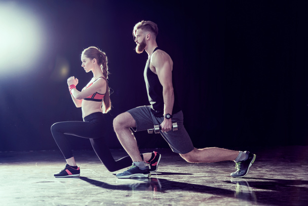 Side view of handsome sportsman and young fit woman training together on black - Photo, Image
