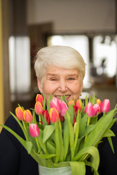 elderly smiling woman with flowers - Zdjęcie, obraz