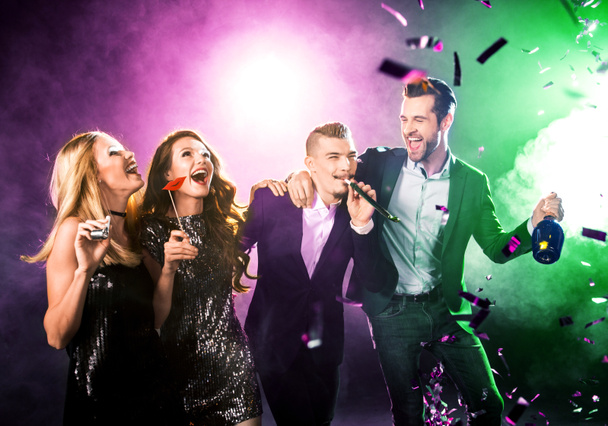 Grupo de amigos felices divirtiéndose con botella de champán y confeti
 - Foto, Imagen