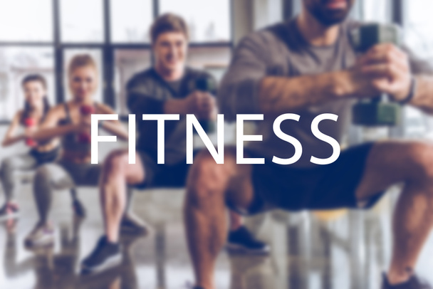 grupo borroso de jóvenes atléticos en ropa deportiva con pesas haciendo ejercicio en el gimnasio, inscripción de fitness
 - Foto, imagen