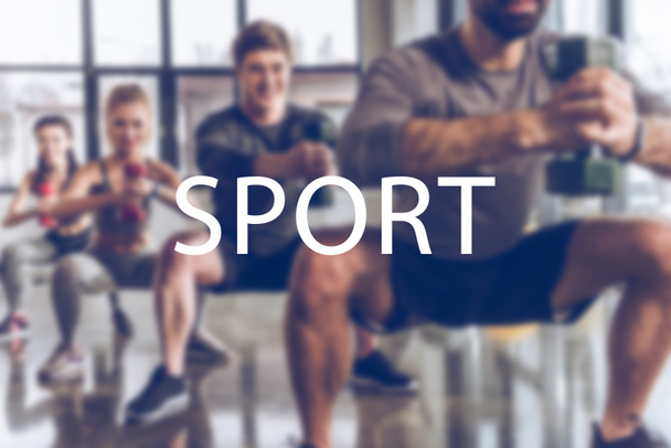 gruppo sfocato di giovani sportivi in abbigliamento sportivo con manubri che si esercitano in palestra, iscrizione sportiva
 - Foto, immagini