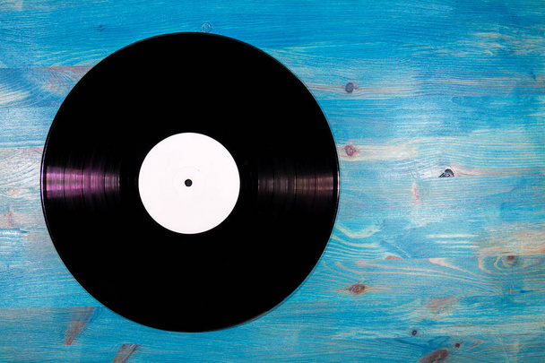 Black color vinyl record with white label on blue wooden background - Photo, Image