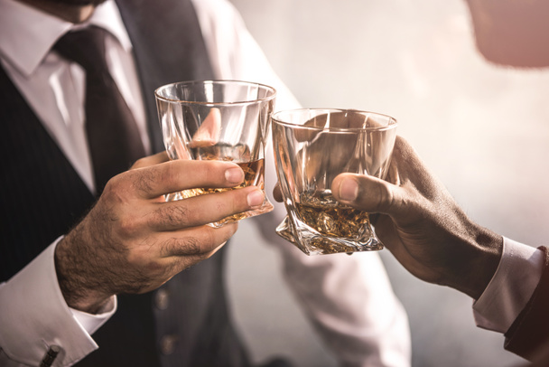 vágott lövés a két férfi ruházat csengő whiskey üvegek - Fotó, kép