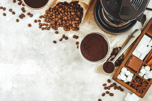 Variety things for prepare coffee. Roasted beans, ground coffee, scoop, electric coffee machine and assortment of sweets and spices to eat with on light background. Top view copyspace - Φωτογραφία, εικόνα