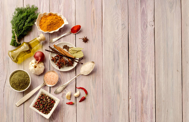 A különböző fűszerek, olíva olaj, a lemezek és a kanál és a konyhai fűszernövények a lila, fából készült tábla közelről. - Fotó, kép