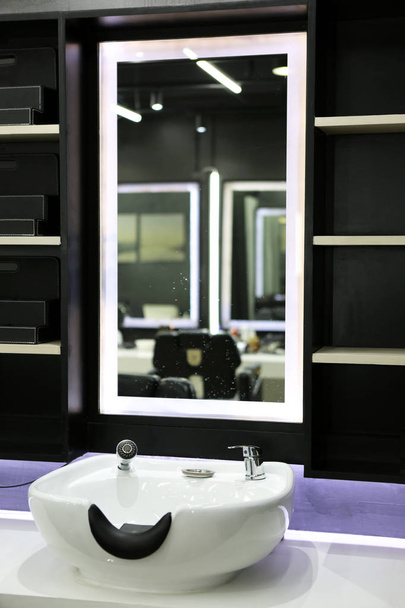 un fregadero de lavado de cabello frente a un espejo en el salón de belleza
 - Foto, imagen