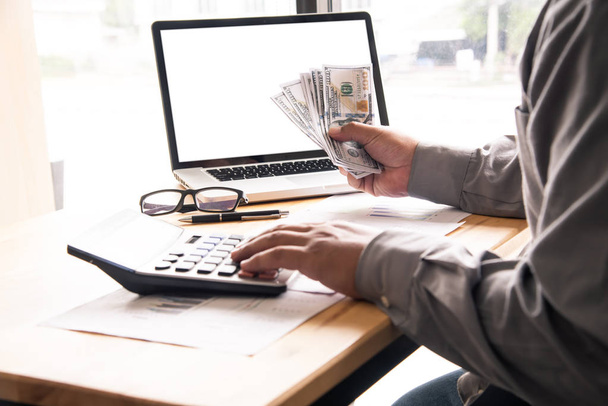 бизнесмен, использующий калькулятор и держащий деньги
  - Фото, изображение