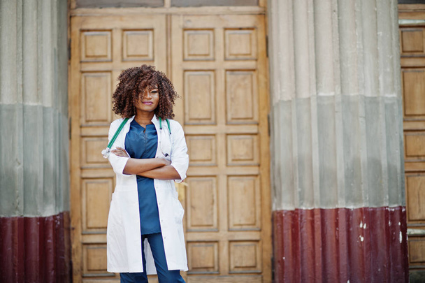 African american doctor female at lab coat with stethoscope outdoor against clinic door. - Valokuva, kuva
