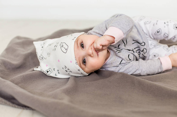 Cute baby on white background.Close up head shot of a caucasian baby girl, six months old baby in a grey clothes and white hat looking at camera - Фото, зображення