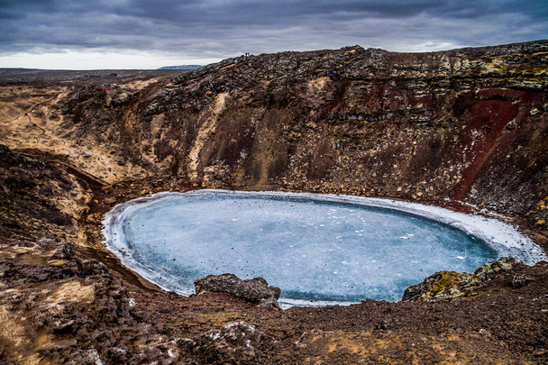 Cráter volcánico Kerid y su estanque azul, Golden Circle, Islandia. Los colores invernales del hermoso Kerio, o cráter Kerid en el oeste de Islandia. Roca volcánica roja, verdes laderas musgosas y un círculo de romper el hielo en un lago turquesa
. - Foto, Imagen
