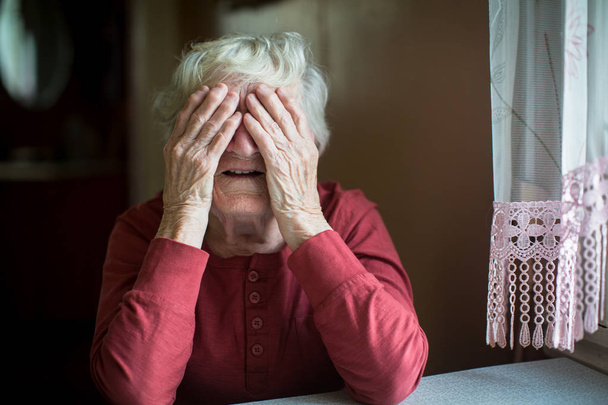 Ηλικιωμένη γυναίκα καλύπτει πρόσωπο με ζαρωμένα χέρια.  - Φωτογραφία, εικόνα