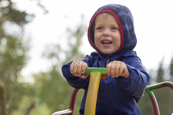 笑顔で幸せな子供をクローズ アップ再生遊び場の背景でカルーセル グッズ - 写真・画像