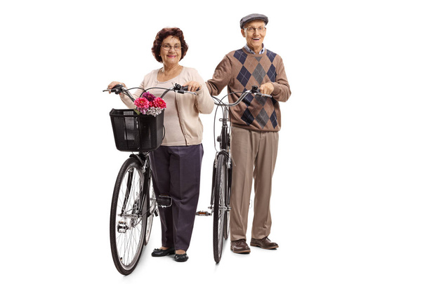 Full length portrait of an elderly man and an elderly woman with bicycles isolated on white background - 写真・画像