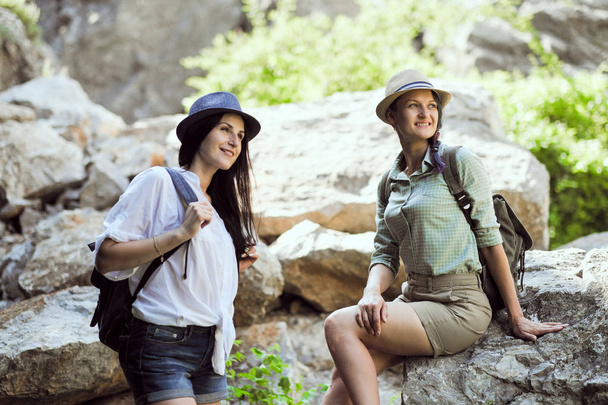 Two beautiful young girls travel in the mountains and enjoy the view of the landscape of stones. - Foto, Imagen