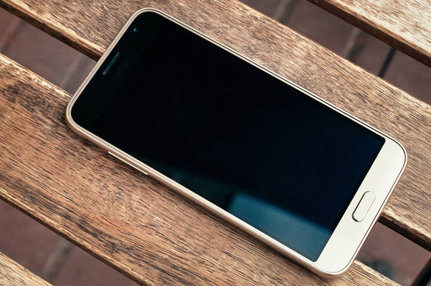 Pohled shora jediný bílý smartphone s černými prázdná obrazovka pro návrh na vinobraní grunge dřevěný stůl. Detailní obrázek, efekt zrnění filmu - Fotografie, Obrázek
