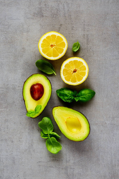 Flat lay of organic avocado, lemon and basil on light background from above with copyspace. - Фото, изображение