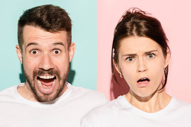 Closeup portrait of young couple, man, woman. One being excited happy smiling, other serious, concerned, unhappy on pink and blue background. Emotion contrasts - Foto, Bild