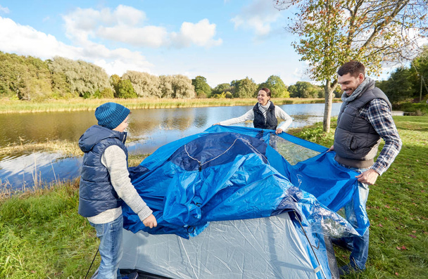 happy parents and son setting up tent at campsite - Foto, Bild