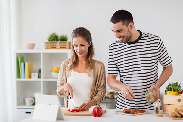 happy couple with tablet pc cooking food at home - Foto, imagen