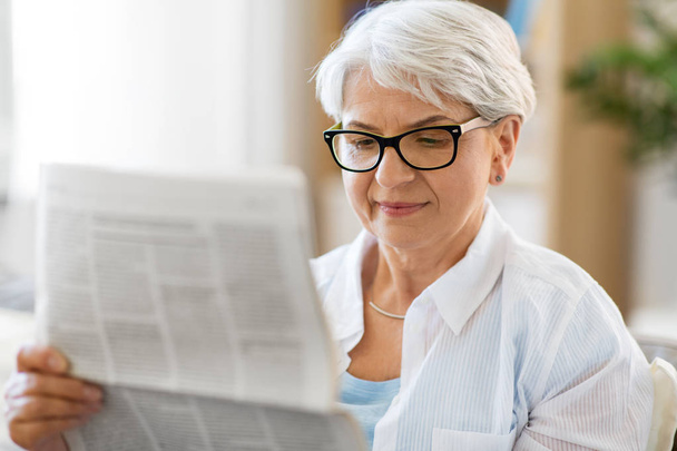 portrait of senior woman reading newspaper at home - Foto, Imagem