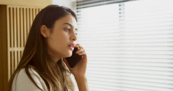 Mujer hablando por teléfono móvil en la sala de estar en casa 4k
 - Metraje, vídeo
