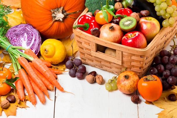 Assortment of fresh and ripe autumn vegetables and fruits on a rustic wooden table painted on white - Photo, Image