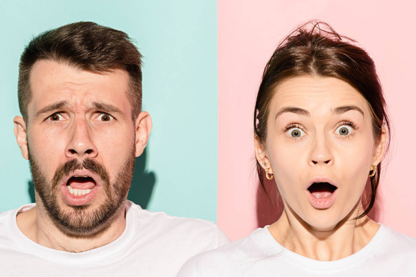 Closeup portrait of young couple, man, woman. One being excited happy smiling, other serious, concerned, unhappy on pink and blue background. Emotion contrasts - Photo, image