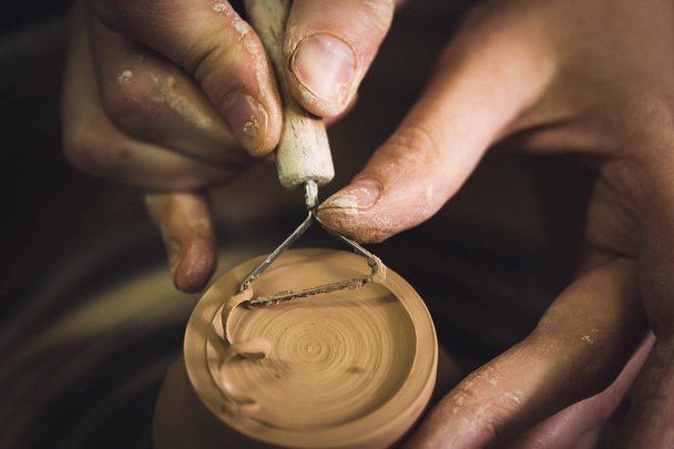 Master removes the top layer of clay on pot with a special tool. - Foto, Imagem