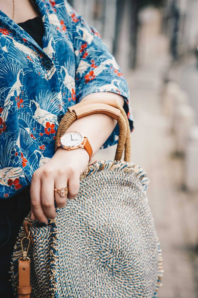 ストリート スタイル ファッションの詳細。クローズ アップ、ファッションのブロガー夏シャツと白と茶色のアナログ腕時計時計、美しいラウンドわら財布を持って身に着けています。完璧な夏ファッション ・ アクセサリー. - 写真・画像