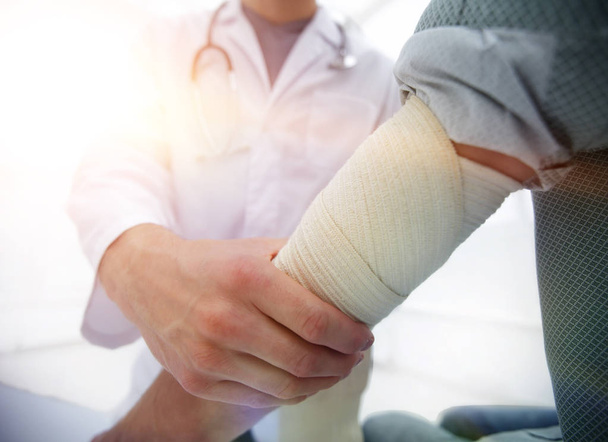 Orthopedist applying bandage onto patients hand in clinic - Фото, зображення