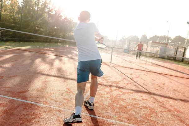  Man playing tennis in the morning in sunlight - Fotó, kép