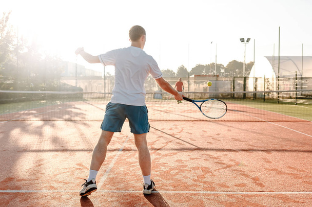  Man playing tennis in the morning in sunlight - Photo, Image