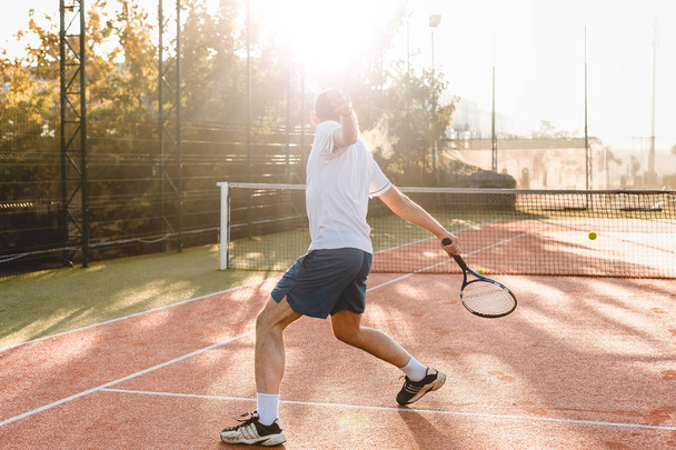  Man playing tennis in the morning in sunlight - Photo, Image