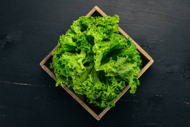 Green lettuce in Wooden box. On a wooden background. Top view. Copy space. - Foto, imagen