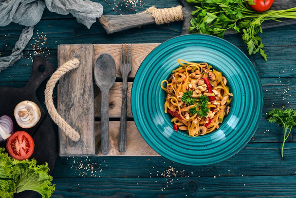 Pasta with mushrooms and vegetables. Italian cuisine. On a wooden background. Top view. Copy space. - Photo, image