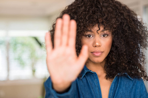 Африканская американка с открытой рукой делает знак стоп с серьезным и уверенным выражением лица, защитный жест
 - Фото, изображение