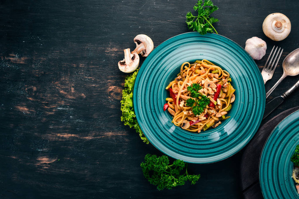 Pasta with mushrooms and vegetables. Italian cuisine. On a wooden background. Top view. Copy space. - Foto, Imagem