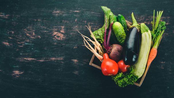 A set of fresh vegetables in a wooden box. On a wooden background. Top view. Copy space. - Foto, afbeelding