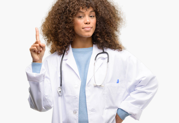 Afrikkalainen amerikkalainen lääkäri nainen, lääkäri työskentelee onnellinen ja yllättynyt hurraavat ilmaista wow ele osoittaa ylöspäin
 - Valokuva, kuva