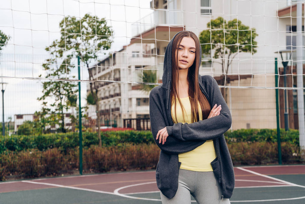 beautiful strong long-haired girl posing on outdoor sports field after playing volleyball - 写真・画像