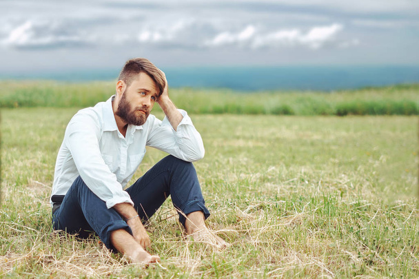 muž sedí smutně v trávě - Fotografie, Obrázek
