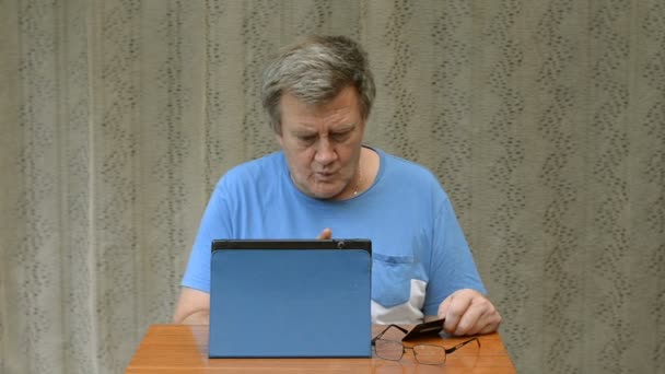 Elderly person tries to make a purchase on the Internet using a tablet and a credit card. But he can not do it. - Materiał filmowy, wideo