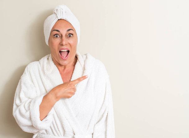 Красива жінка середнього віку, мокре волосся в рушнику дуже щаслива вказуючи рукою і пальцем
 - Фото, зображення
