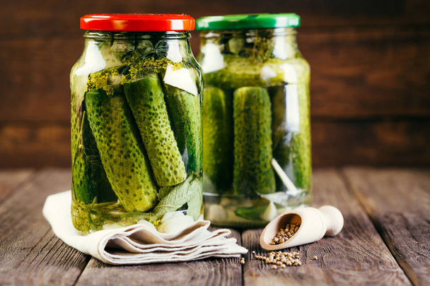 komkommers in een pot op een houten ondergrond, ingeblikte groenten oogsten, pickles - Foto, afbeelding