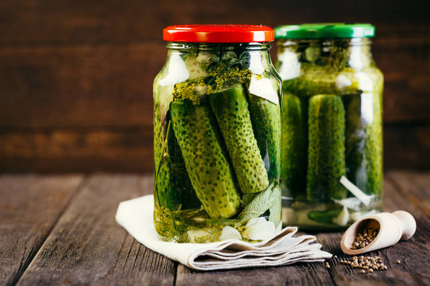 komkommers in een pot op een houten ondergrond, ingeblikte groenten oogsten, pickles - Foto, afbeelding