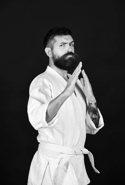 Karate man with serious face in uniform. Taekwondo master practices defense posture. - Φωτογραφία, εικόνα