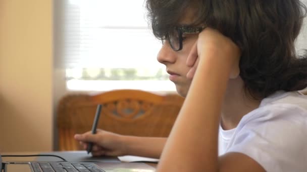 handsome modern boy teenager working on a graphic tablet. he looks at the laptop screen. 4k, slow motion - Materiaali, video