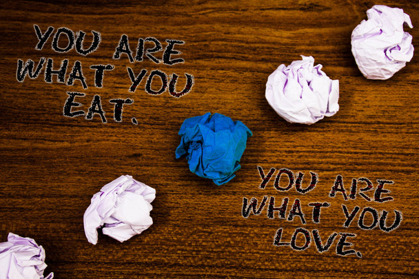 Word writing text You Are What You Eat. You Are What You Love.. Business concept for Start to eat healthy food Brown woody desktop four white crumpled paper balls central blue one - Fotografie, Obrázek