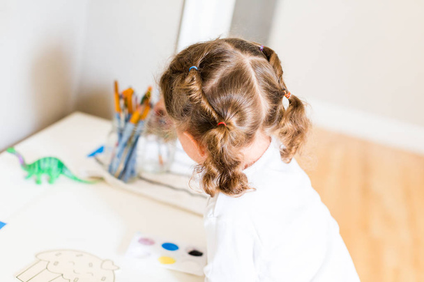Malá holčička kreslení u svého stolu doma. - Fotografie, Obrázek